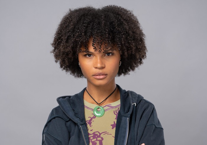 Jasmine Fisher in EastEnders wearing a blue hoody and a green charm around her neck