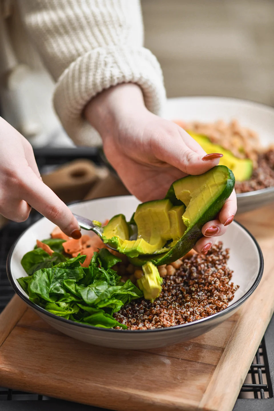Female Adding Avocado Slices to Salad Bowl for Extra Healthy Fats