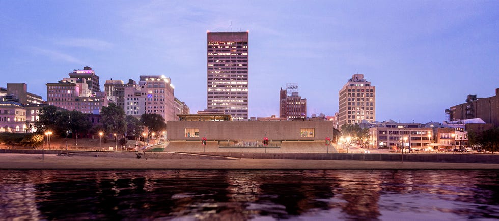 Cityscape featuring a modern building by a waterfront at dusk. Cityscape featuring a modern building by a waterfront at dusk.