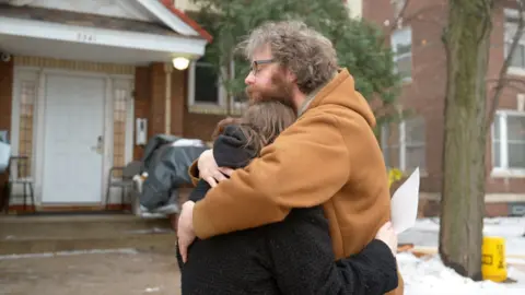 Eloise Alanna/BBC A man and woman hug near the site of the Minneapolis shooting