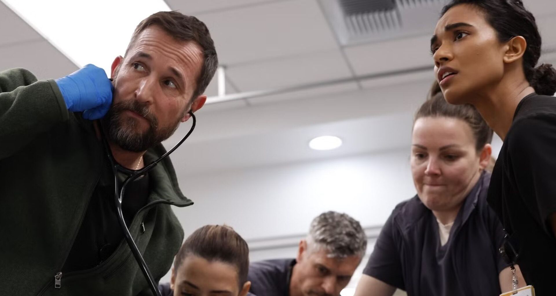 A team of doctors crowd around an operating table