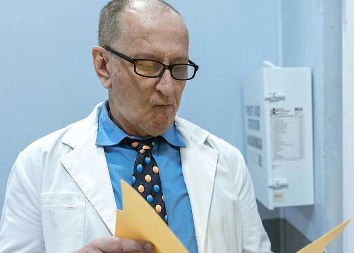 Doctor in white coat and glasses reviewing patient files, illustrating unprofessional things doctors have said to patients.