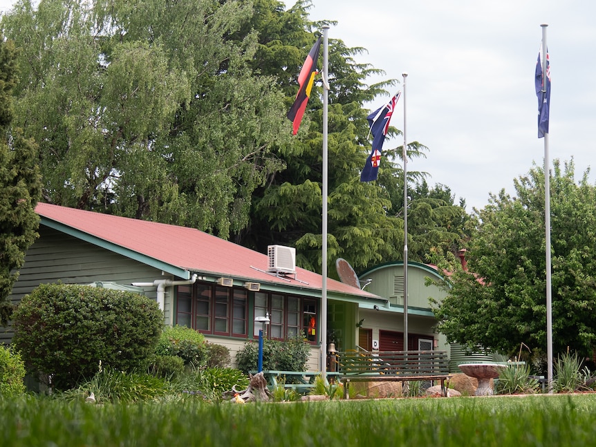 A small school building with flags out the front.