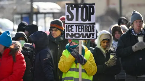 EPA A woman holds a sign reading 'Stop ICE terror now!' at a makeshift memorial for Alex Pretti in south Minneapolis
