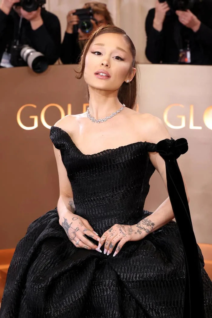 Ariana Grande on a red carpet, surrounded by photographers