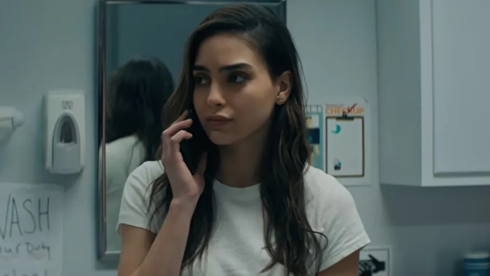 Melissa Barrera holding up a phone and looking to her left in Scream.