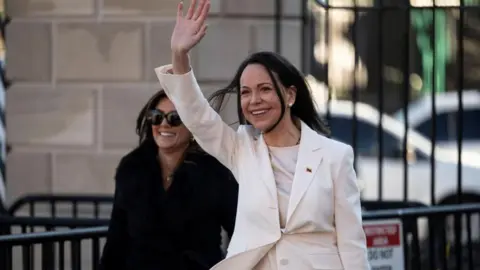 Reuters Machado wears a white suit and waves after leaving the White House
