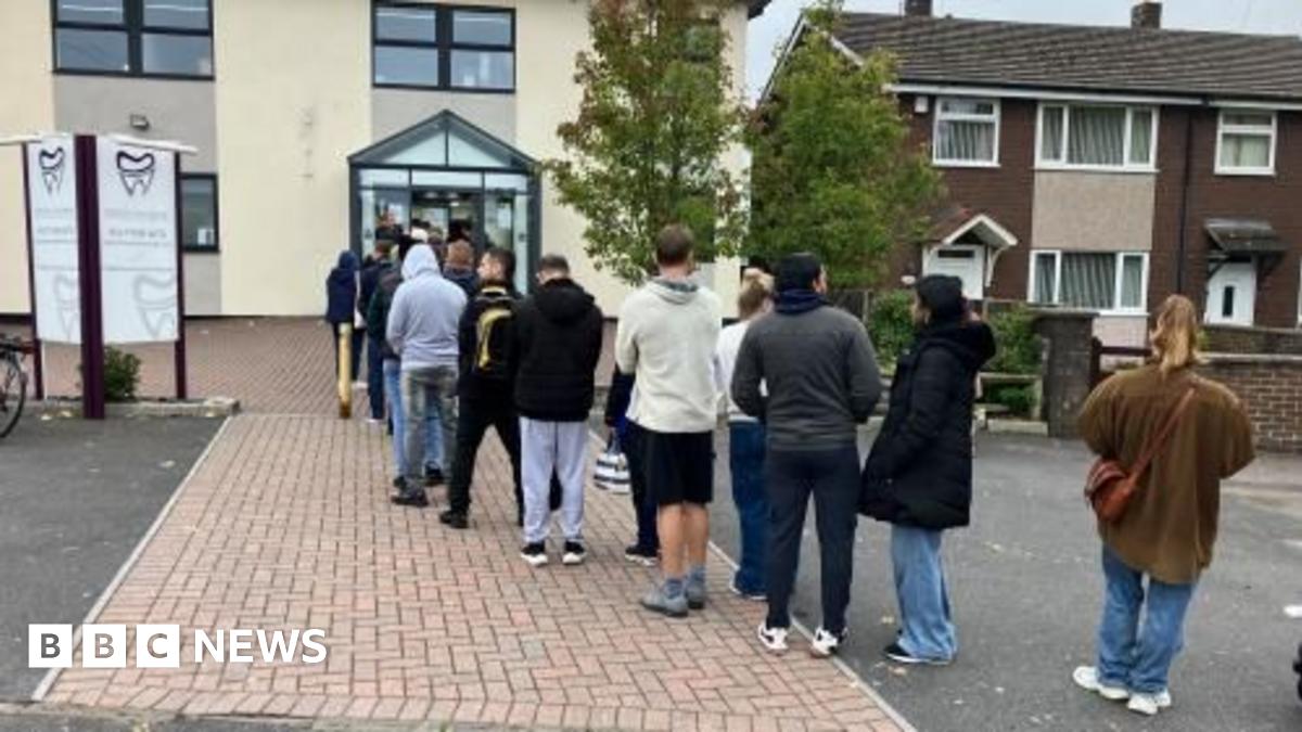 A queue of dozens of people is formed outside a dentist's practice.