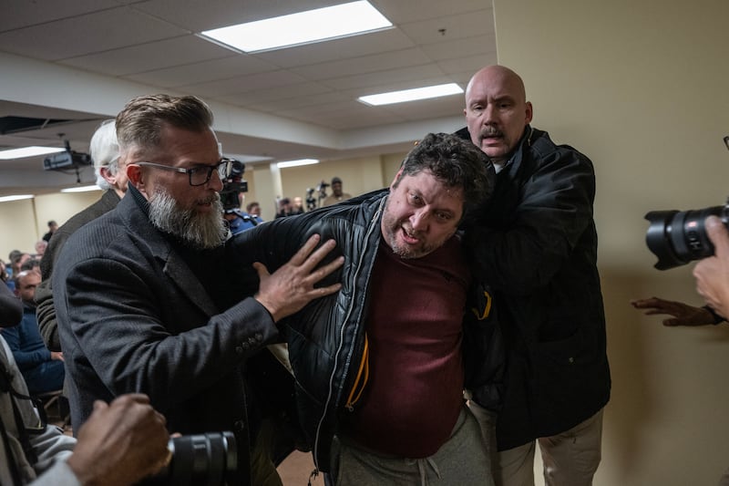 A man is removed from a town hall in handcuffs after  Ilhan Omar was sprayed with a strong-smelling liquid. Photograph: Victor J Blue/The New York Times
                      