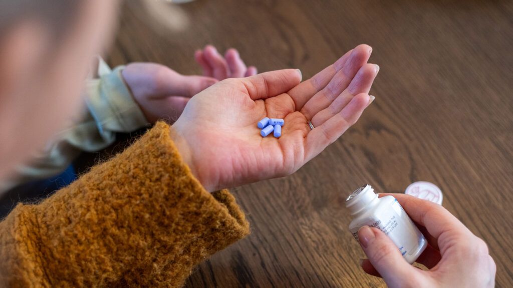 A person holding pills in the palm of their hand.