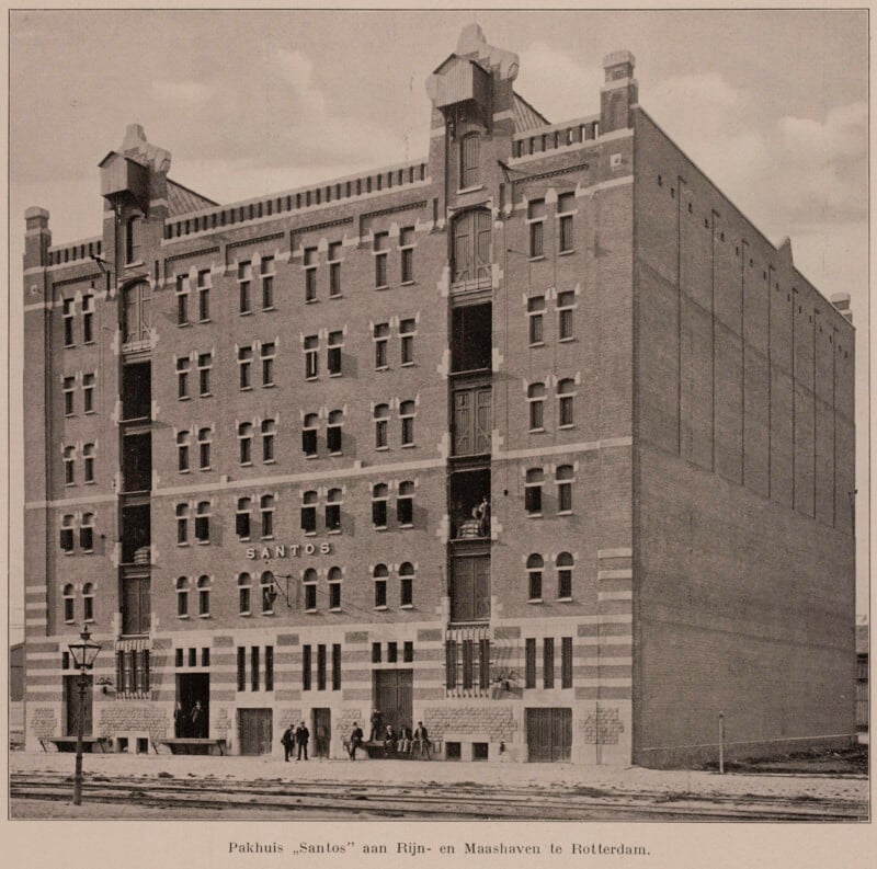 Historic black-and-white photo of a large brick warehouse labeled "Santos," with arched windows and people standing in front, located at Rijn- en Maashaven in Rotterdam.