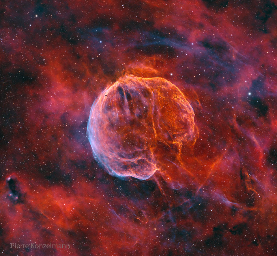 A colorful starfield surrounds a giant nearly-spherical 
nebula that has texture and stripes like watermelon. 
The lower right of the nebula is open making it appear
like a medulla oblongata -- the stem that connects to 
a brain. 
Please see the explanation for more detailed information.