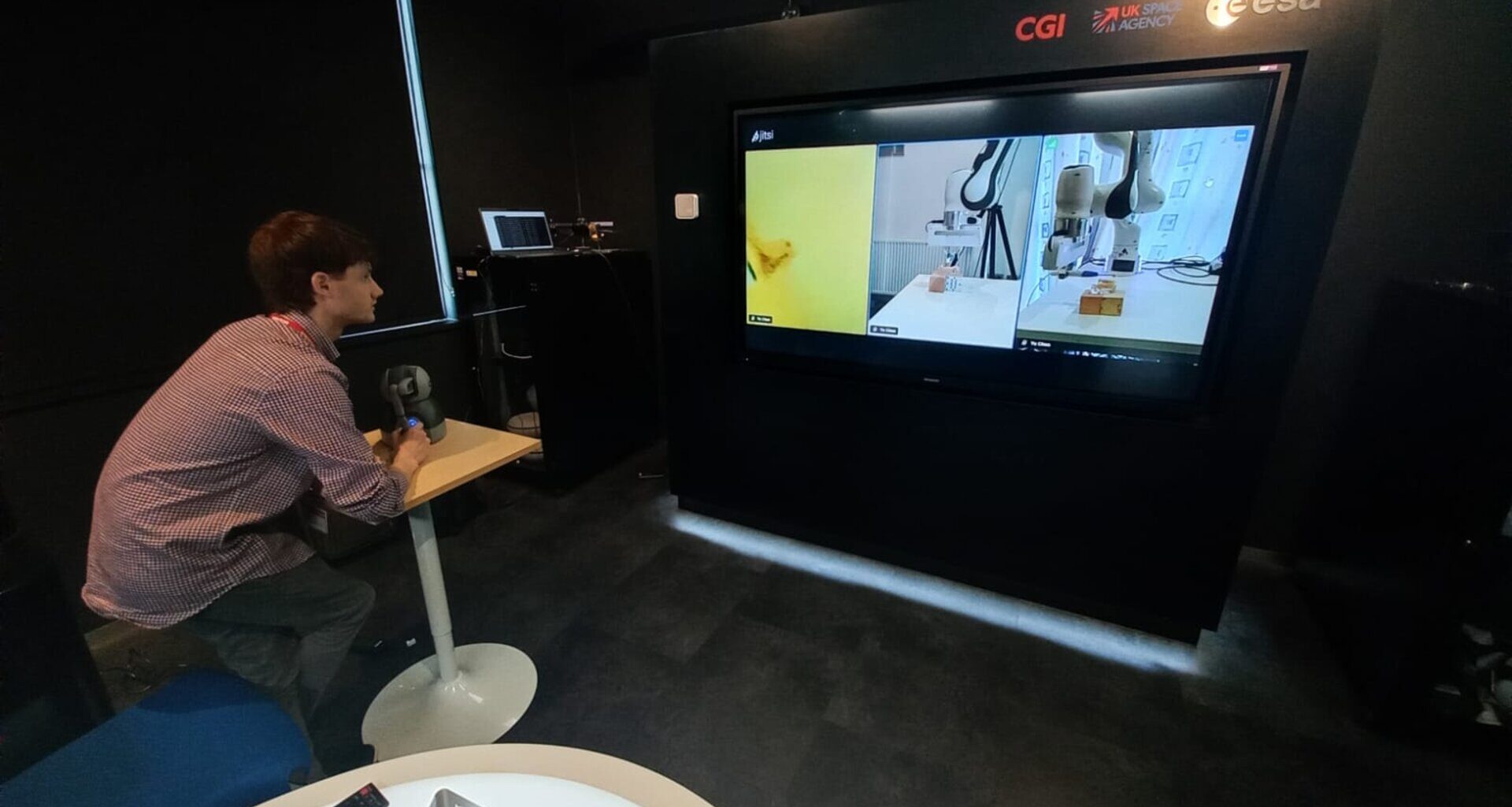 A dentist at ESA’s European Centre for Space Applications and Telecommunications (ECSAT) in the UK controlling a robotic arm at the University of Glasgow’s SCENE facility at Loch Lomond.