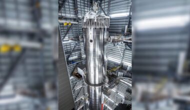 a tall silver rocket upright in a hangar
