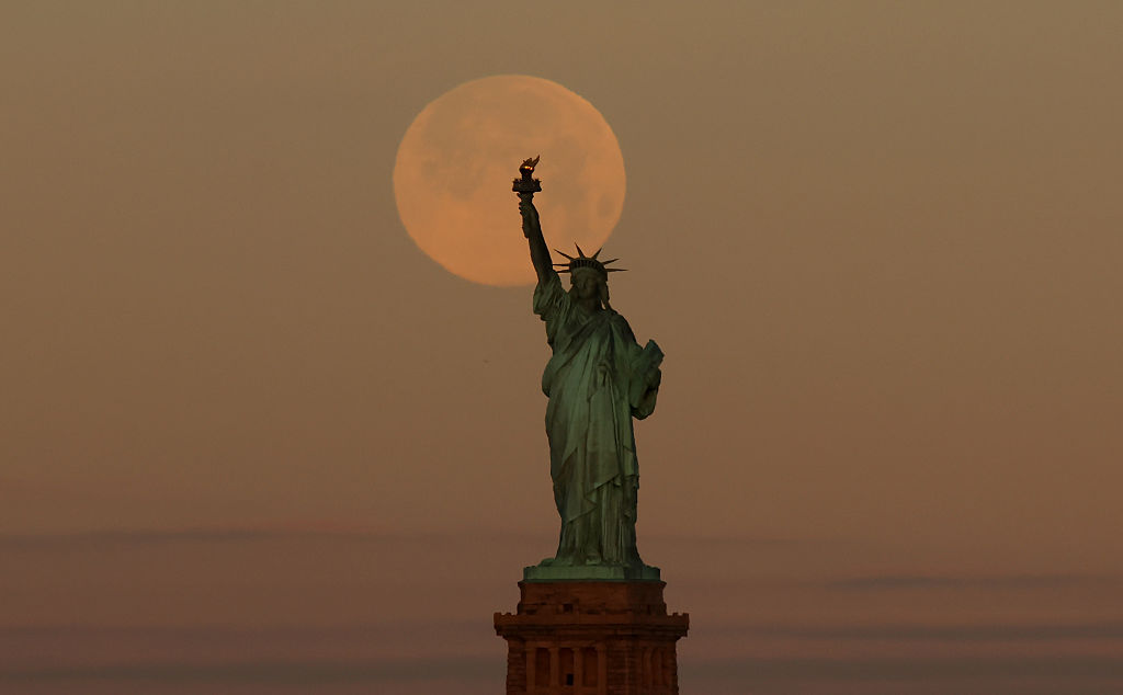 Wolf Moon behind the Statue of Liberty in New York City.