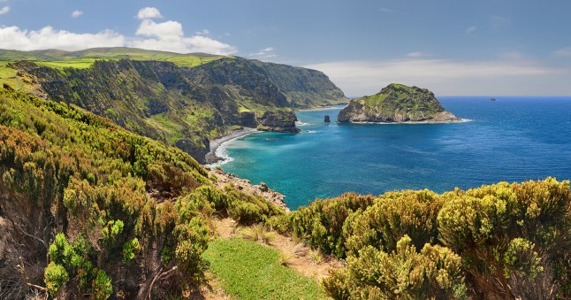 An aerial view of The Azores' lush green coast and blue sea.
