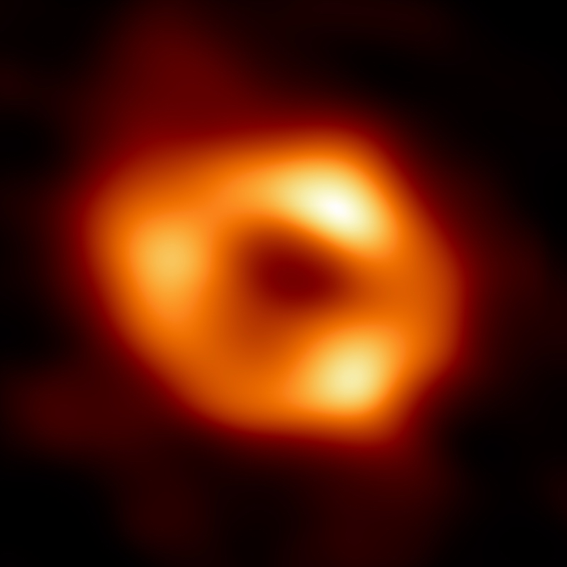 Black hole: Fuzzy glowing yellow and orange donut with black center and 3 brighter spots along the ring.