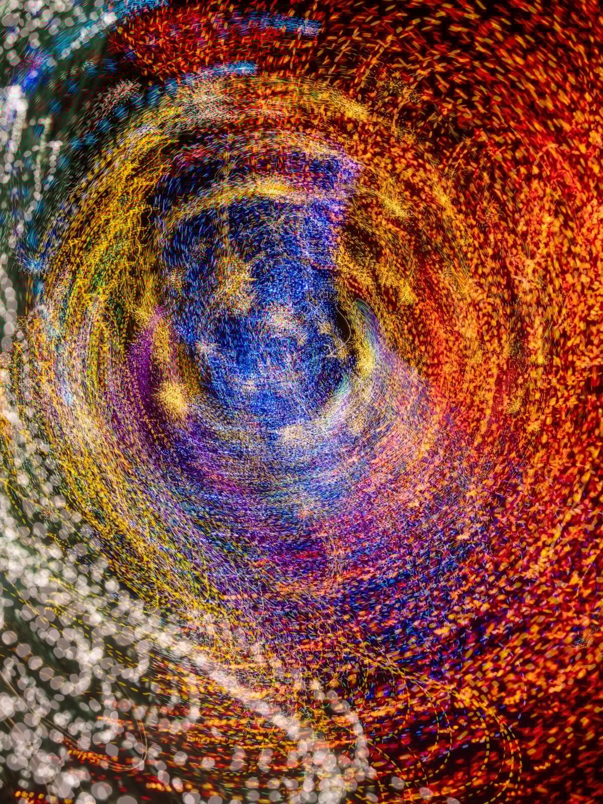 A swirl of colorful, blurred lights including red, blue, yellow, and white, creating a vibrant, abstract spiral pattern that suggests movement and energy.