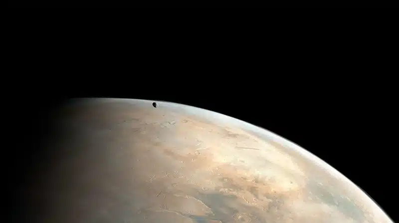 Phobos Drifts Above Mars As A Dust Storm Stirs Across The Tharsis Region, Seen From Mars Express.