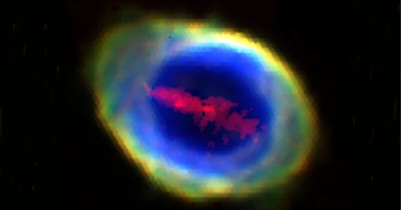 A glowing, colorful nebula with a bright yellow and green outer ring, a vivid blue center, and red cloud-like formations inside, set against a black background.