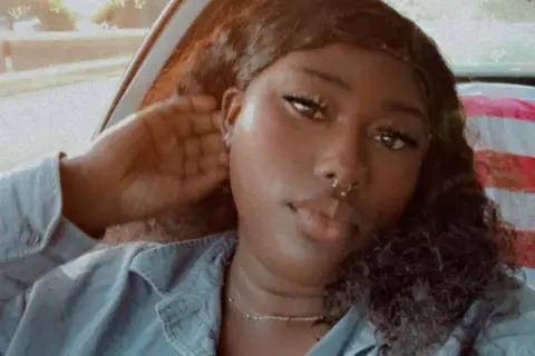 Selena Cooper A woman wearing a denim shirt poses for a photo.