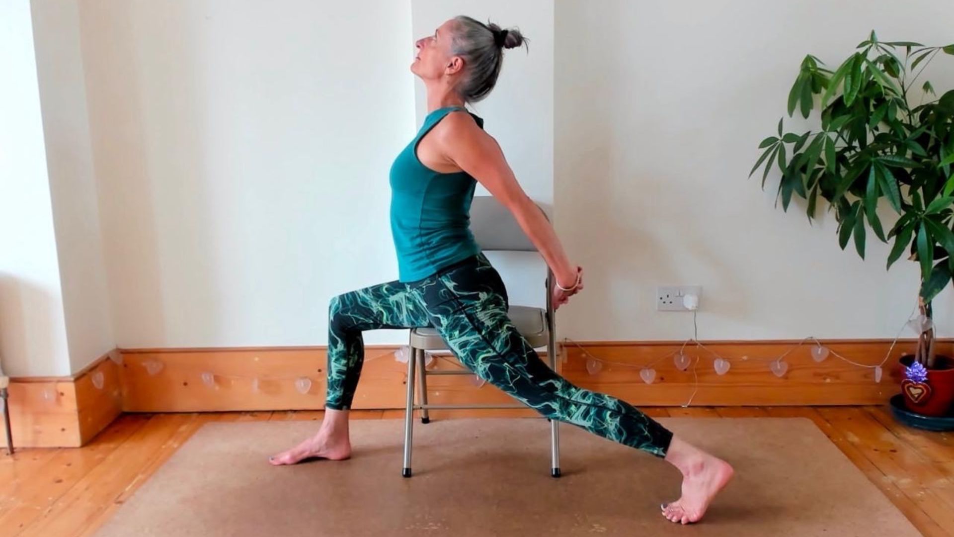 Dina Cohen demonstrates the seated warrior pose using a chair for support