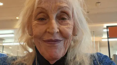 Susan Thorkildsen A picture of a woman with shoulder-length grey hair in a blue jumper