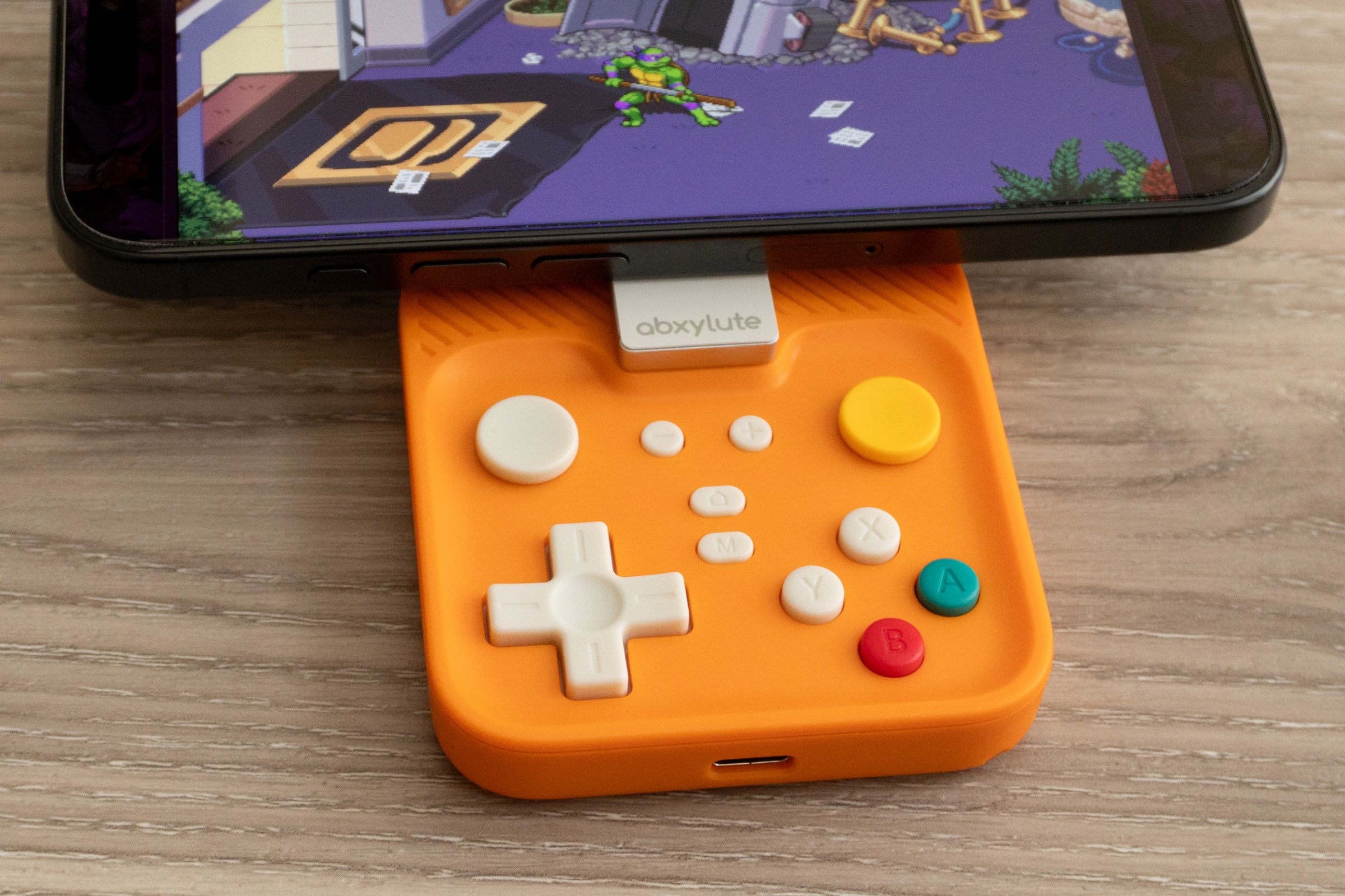 The Abxylute M4 controller attached to an iPhone 16 Pro playing a TMNT game.
