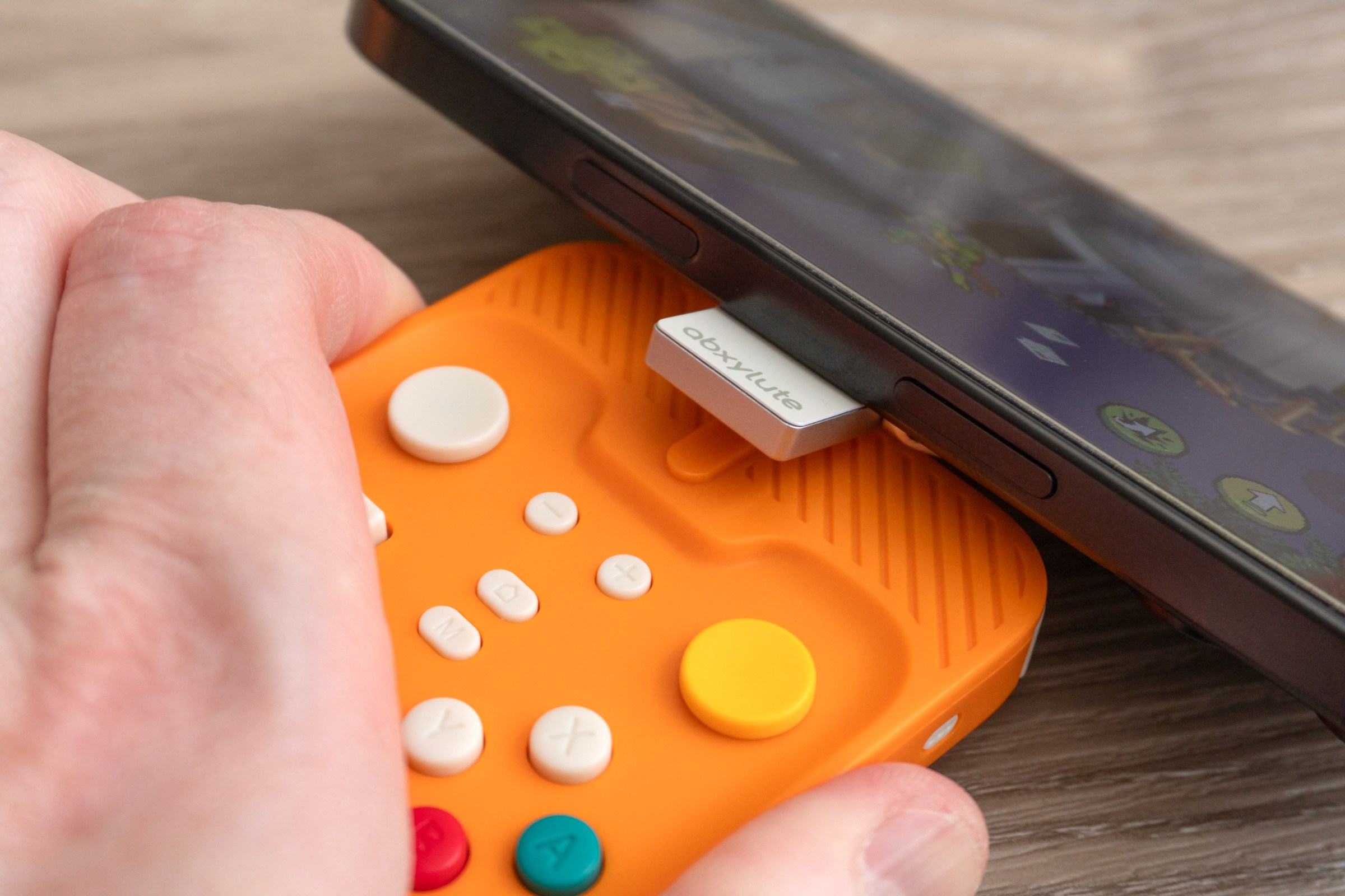 The Abxylute M4’s magnetic mount attached to an iPhone shown disconnecting from its controller.