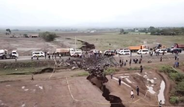 “People and vehicles gather beside a deep ground fissure that ripped across a road in Kenya, part of the East African Rift zone.”