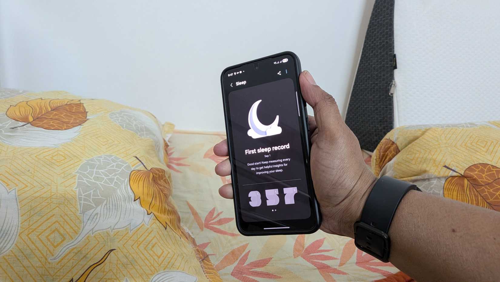 An arm wearing the Galaxy Watch 4 and holding a Samsung Galaxy S24 showing the sleep tracking page.