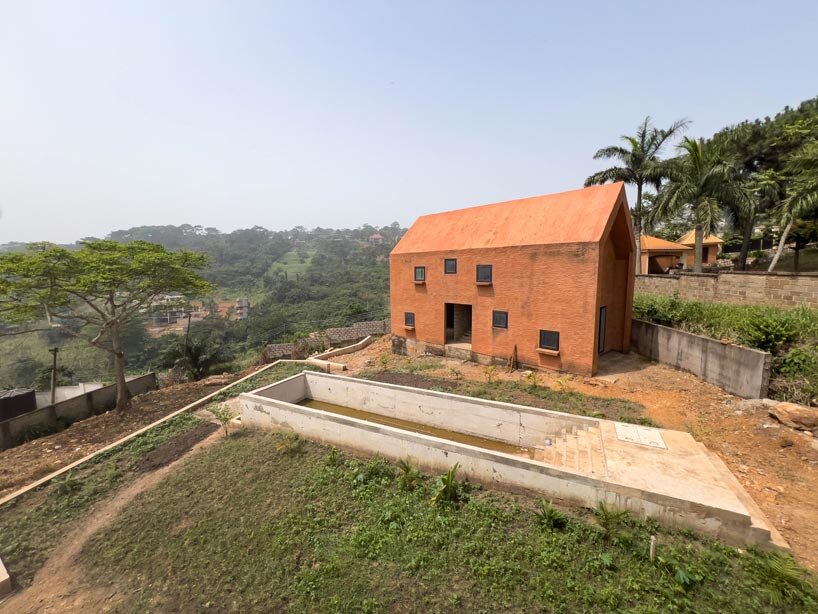 clay-pigmented monolithic villas emerge from ghana’s red earth landscape