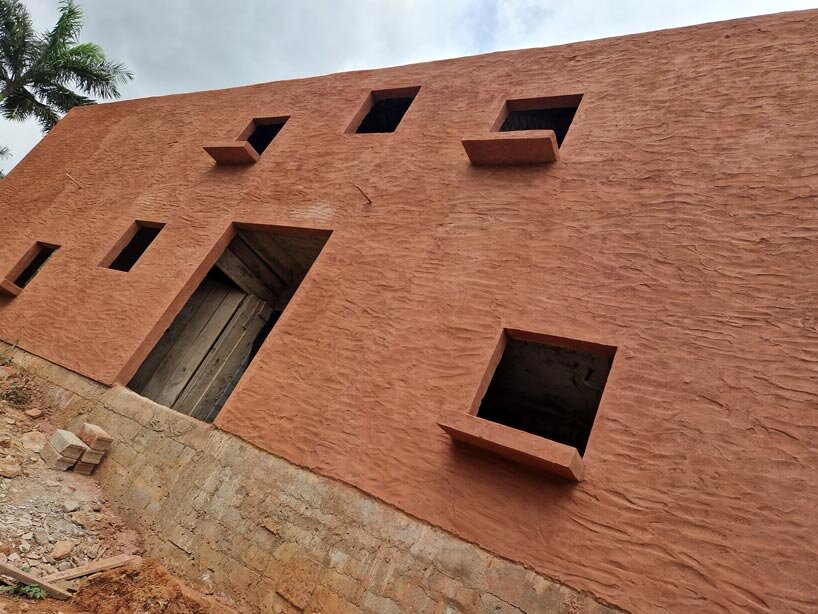 clay-pigmented monolithic villas emerge from ghana’s red earth landscape