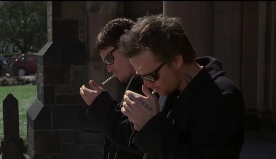 Sean Patrick Flanery and Norman Reedus in shades smoking cigarettes