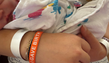 hand with an orange bracelet that says I gave birth