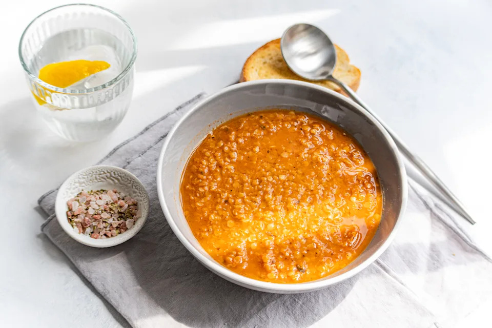 Overhead view of a bowl of Traditional Greek lentil soup (fakes) with toasted bread and a glass of lemon water