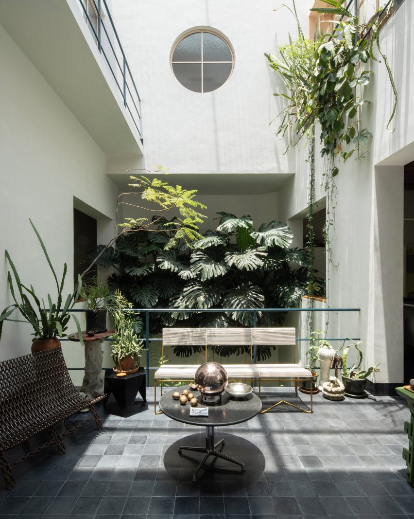 Balcony with an eclectic collection of furniture and decor, overlooking an atrium filled with plants
