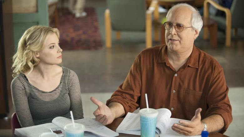 Gillian Jacobs and Chevy Chase as Britta and Pierce sitting at a table on Community