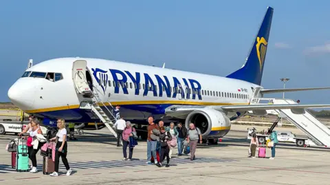 Getty Images A Ryanair plane with passengers getting off and walking across the tarmac.