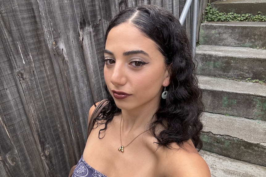 A selfie of a girl in a blue strapless top with curly hair.