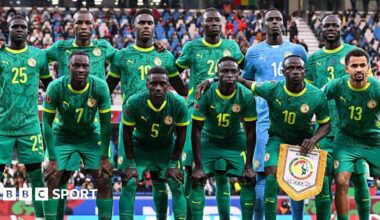 Senegal players wearing green shirts, shorts and socks pose for a team photo