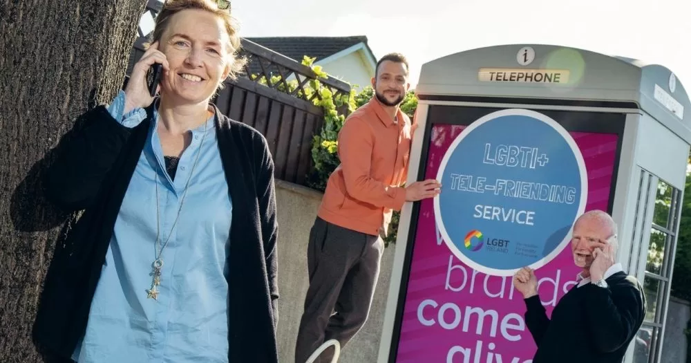 Three team members from LGBT Ireland pose with phones and advertising material promoting the Telefriending service.