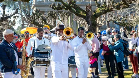 Heidi Alletzhauser/California Academy of Sciences Press Office A brass band playing drums and horns walking through a crowd