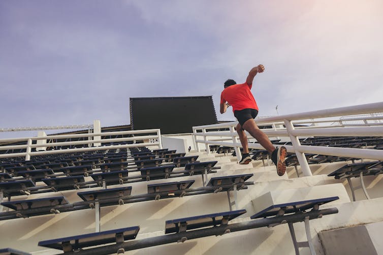 A man sprints up some stairs at a sports stadium.