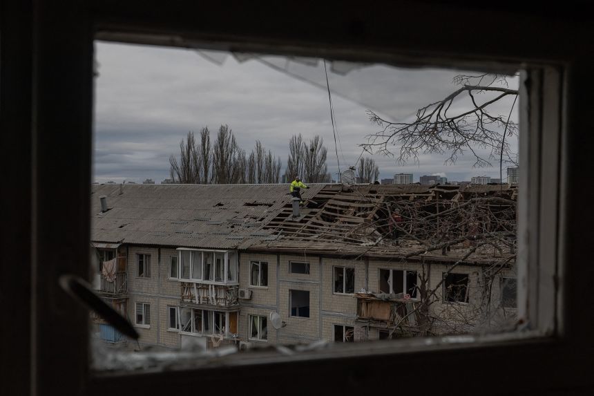 Workers clear debris from the roof of a damaged residential building following a drone strike in Kyiv, on December 23, 2025, amid the Russian invasion of Ukraine.