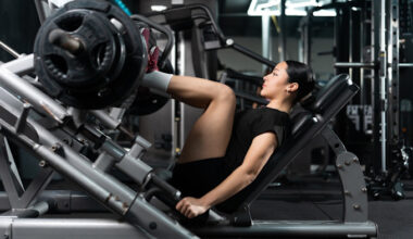 A young woman in athletic wear using a leg press machine, appearing focused while lifting weights in a modern gym.