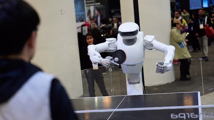 The Sharpa North robot holds a paddle and plays table tennis against a person at a booth during CES 2026