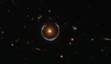 Image of a field of stars with a single bright object in the middle. The object is surrounded by a wispy, distorted ring.