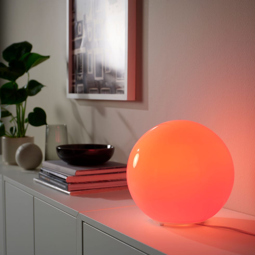 a glowing orange spherical lamp on a console table
