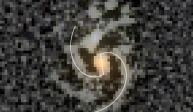 COSMOS-74706: an unsharp mask overlaid onto the F200W, F277W, and F356W filter composition; the white lines are logarithmic spirals fitted to points along the arm structures and a line segment fitted to the approximately North to South aligned bar structure. Image credit: Daniel Ivanov.